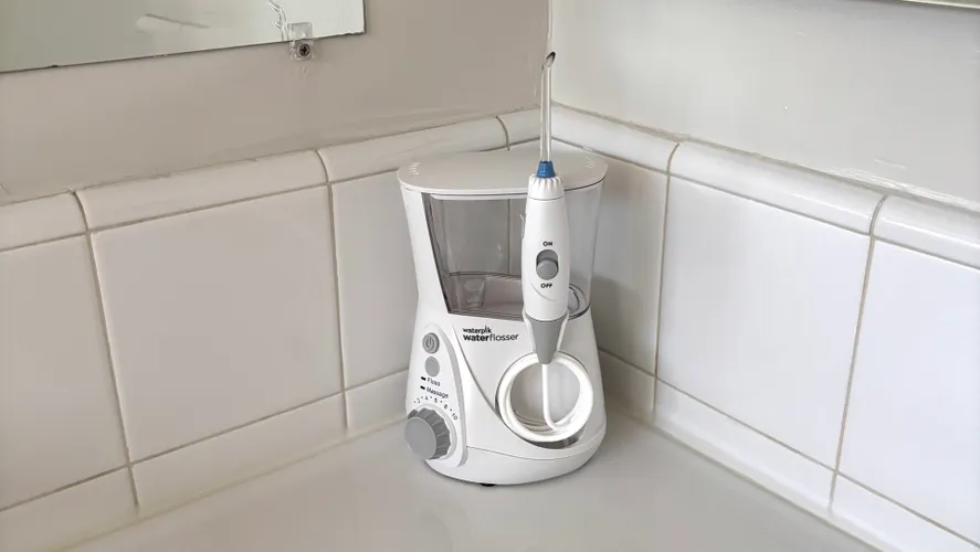 Аэрограф Waterpik Aquarius на белой столешнице в ванной комнате.