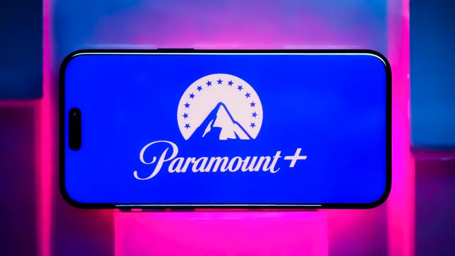 Логотип Paramount Plus на телефоне на неоново-розовом фоне