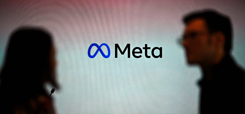 Компания Meta заключила первую в Индии сделку с Reliance по созданию центра обработки данных для ИИ. 2 люди проходят мимо вывески Meta