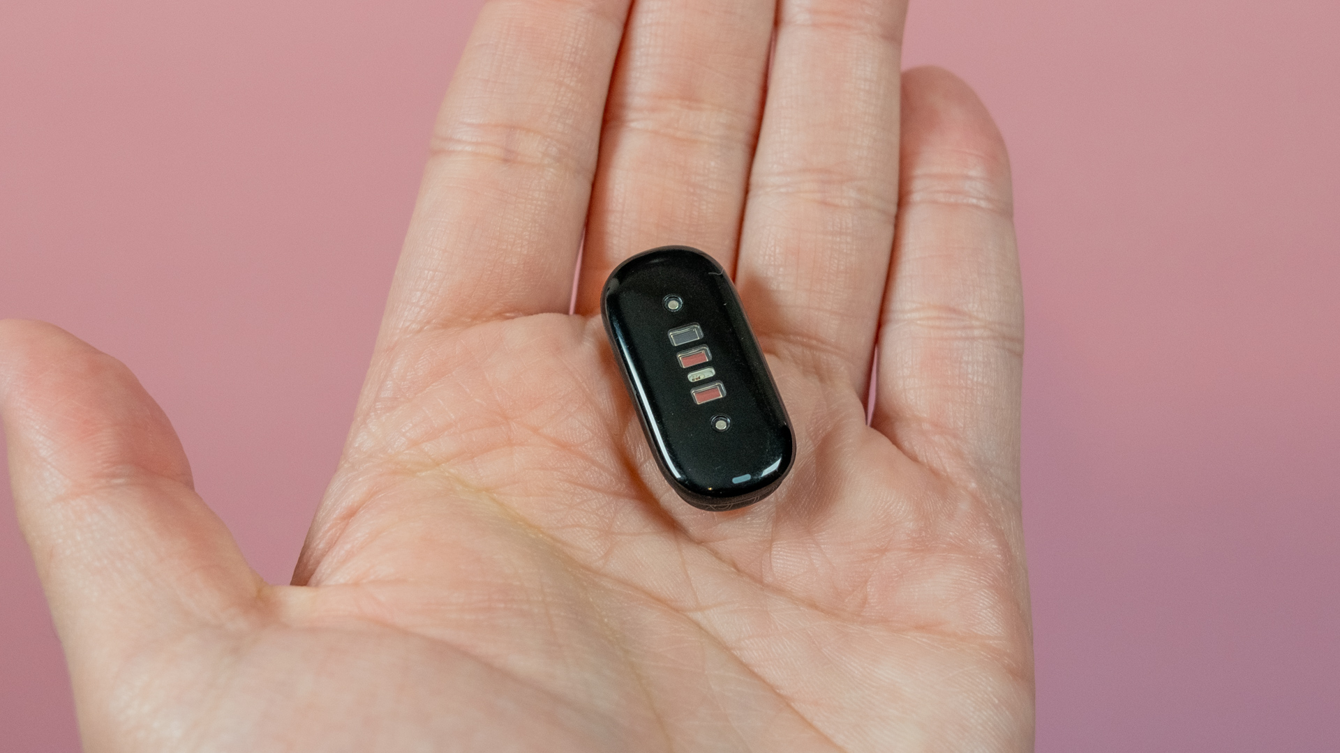 В руке — зарядное устройство для Fitbit Air.