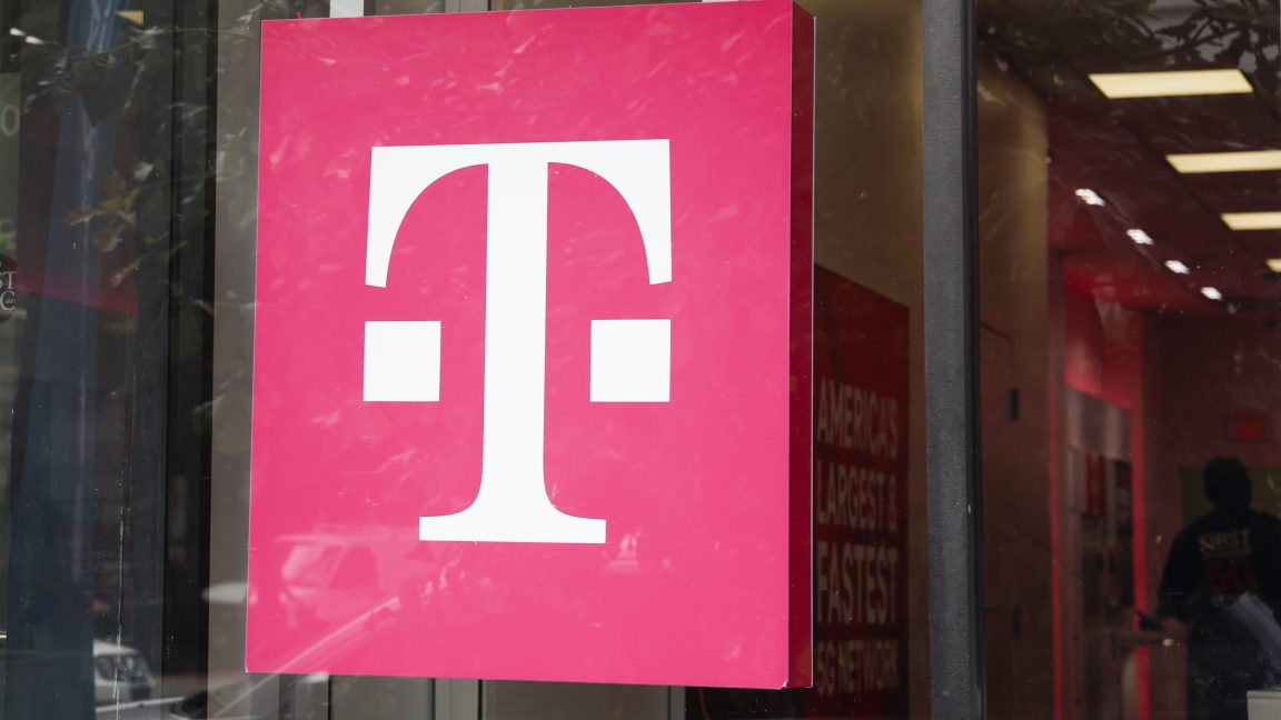 На витрине магазина висит вывеска T-Mobile, представляющая собой большую букву Т.