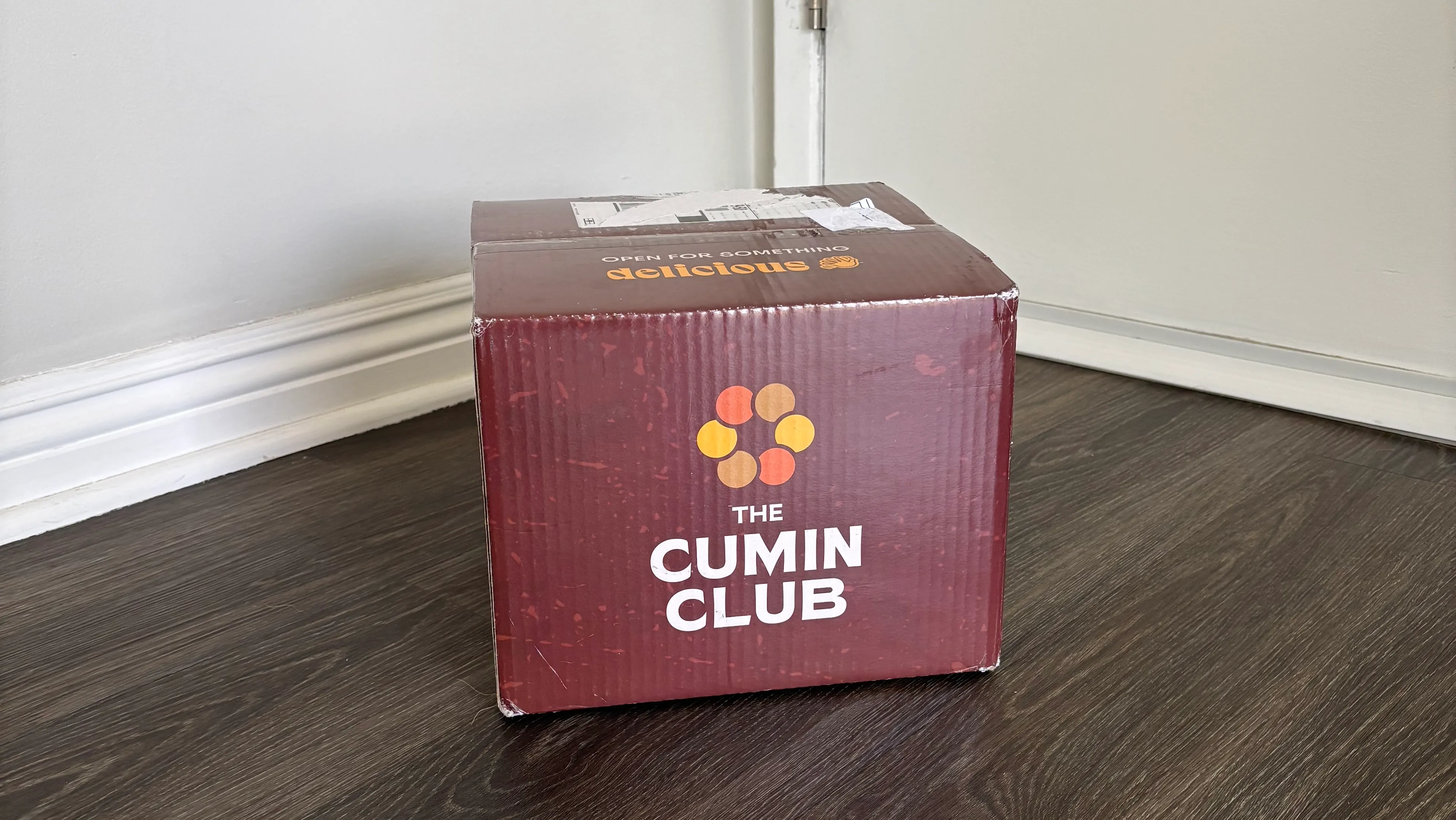 Коробка для отправки от Cumin Club на сером деревянном полу.