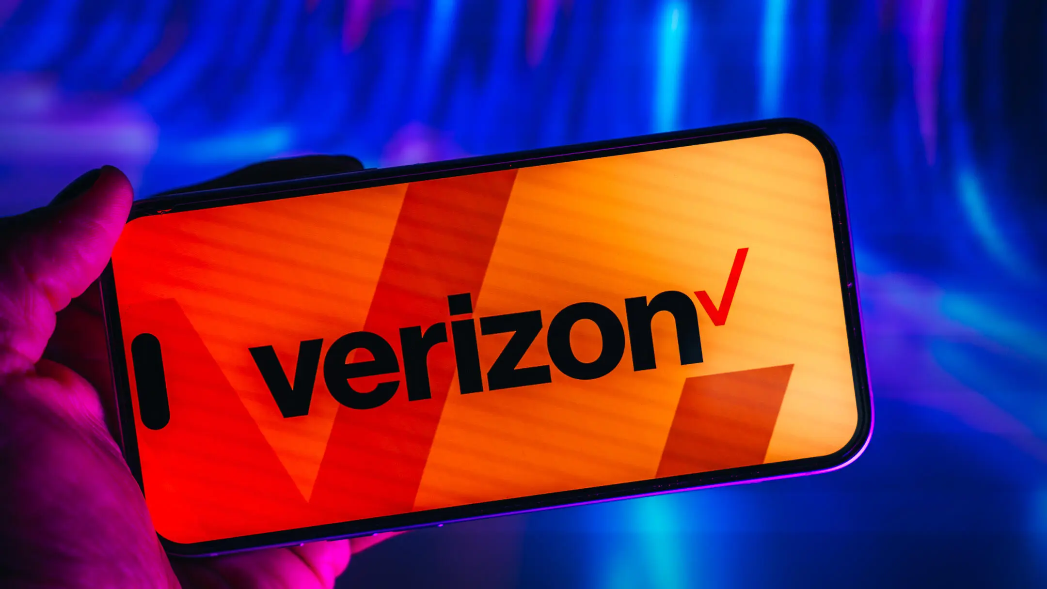 AT&T против Verizon: как выбрать между двумя крупнейшими операторами мобильной связи 4 Значок Verizon отображается на экране мобильного телефона, который держат в горизонтальном положении.