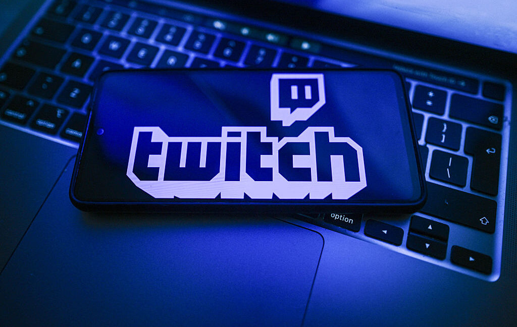 На этой фотоиллюстрации логотип Twitch отображается на смартфоне, расположенном на верхней части ноутбука.