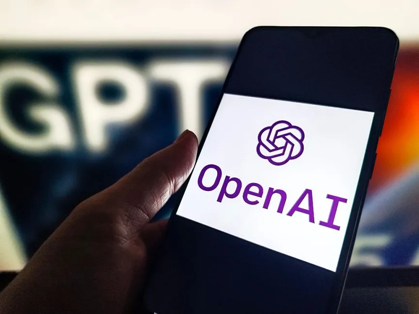 Телефон с логотипом OpenAI, расположенный рядом со знаком ChatGPT.