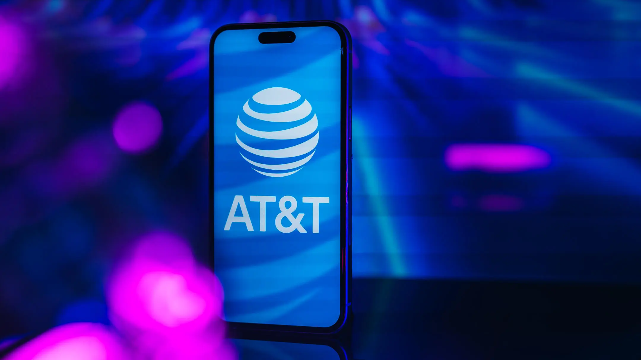 AT&T против Verizon: как выбрать между двумя крупнейшими операторами мобильной связи 3 Логотип AT&T на экране iPhone на синем фоне.