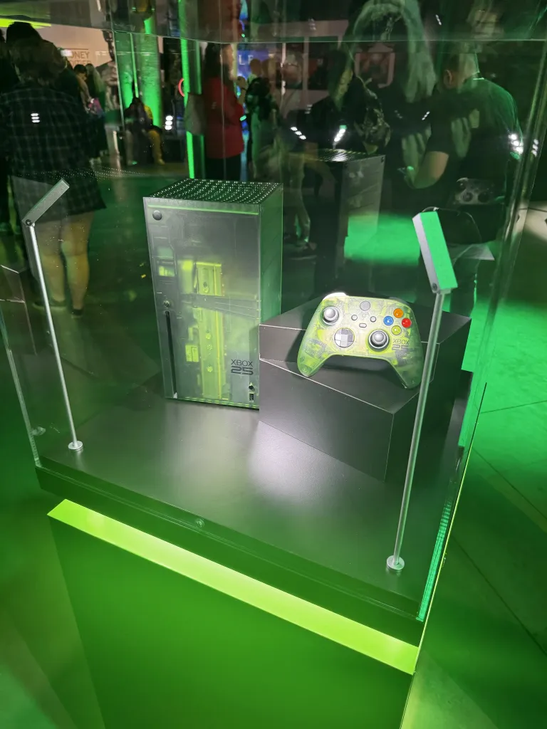 В витрине выставлены Xbox и соответствующий контроллер. Зелёный оттенок подсветки совпадает с зелёным цветом логотипа Xbox.
