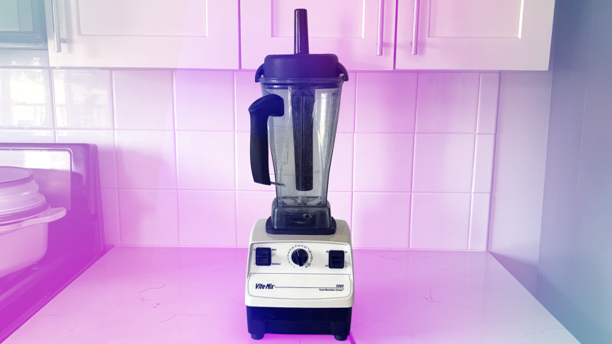 Белый блендер Vitamix 5000 с прозрачным розово-голубым градиентным фоном.