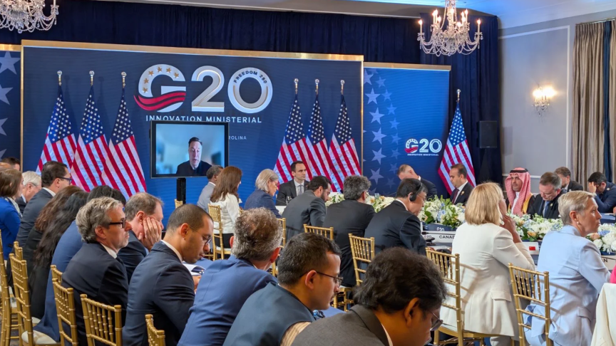 Лидеры сидят за длинным столом перед логотипом G20.